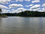 A serene lake surrounded by wooded areas under a cloudy sky, with boat docks visible along the shoreline.