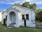 A small, single-story building with white exterior walls, two front doors numbered 922 and 822, and four windows under a clear sky.