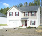 A two-story residential house with white siding and maroon shutters, featuring a garage, a front door with a decorative glass panel, and a small landscaped area by the entrance.
