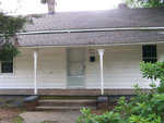 A modest single-story white house with a gabled roof and a covered front porch displaying the number 916.
