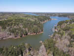 Aerial view of a serpentine river meandering through a forested landscape with docks and boats along the shore.