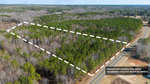 Aerial view of a wooded area with approximate property lines marked by dotted white lines for visual reference, adjacent to a road.