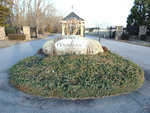 A stone sign with the inscription "peninsula" placed on a landscaped island at the entrance of a residential area during the daytime.