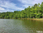 A serene lake with a backdrop of lush green trees under a partly cloudy sky.