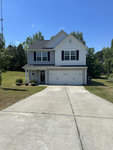A two-story suburban home with a two-car garage and a concrete driveway on a sunny day.