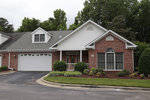 A single-level brick and siding house with a two-car garage and landscaped front yard.