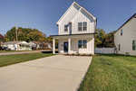 A two-story white house with a covered front entrance and a concrete driveway on a sunny day.
