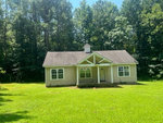 Single-story house at 146 Oak Forest Drive, Henderson NC with a gabled entrance and beige siding, featuring white trim and a green lawn in the foreground.