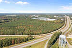 An aerial view of Facet Road interchange with a water tower in the foreground and a mix of industrial buildings and wooded areas in the background.