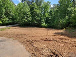 A cleared plot of land in Henderson, NC, bordered by trees under a clear sky at 415 Beechwood Trail.