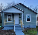 A small, single-story house at 510 Owens Street, Henderson NC, with greenish-blue siding and a white front door. The house has a small porch with a newly constructed wooden railing and steps