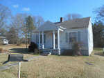 A small, single-story white house at 536 Swain Drive, Henderson NC, with a gabled roof, a front porch with columns, and barren trees in the background, under a clear blue