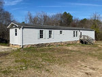Single-story mobile home at 485 Lemay Lane, Henderson NC, set on a stone foundation with a wooden staircase on a clear day.