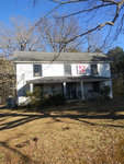 A two-story white house with a front porch, adorned with a star decoration, located at 315 S Lynnbank Road, Henderson NC, surrounded by a lawn with trees under a clear blue sky.