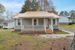 A single-story house at 201 Ranes Drive, Henderson NC, with a tan roof and a front porch, set against a residential backdrop with a front lawn showing patches of dirt and a bare tree