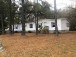 A single-story mobile home with white siding, located at 341 Tower Lane, Henderson NC, in a wooded area with a front staircase leading to the entrance, surrounded by a yard with pine needles.
