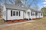A single-story, suburban house at 1260 Horseshoe Bend Road, Henderson NC, with gray siding, white trim, and a gabled roof, featuring red mulch in the front