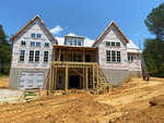 New residential home under construction at 764 Terry Lane, Henderson NC, with exposed wooden framing and house wrap on a dirt construction site with a ladder on the right side.