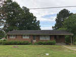 Single-story brick house with a dark roof and an attached carport, located at 254 Vicksboro Road, Henderson NC, situated in a grassy yard with a power line overhead.