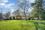 Single-story house with a brick facade and large front yard under a clear sky with shadows cast by bare trees on 2198 N Woodland Road, Henderson NC.