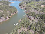 An aerial view of a serene river inlet with docks and boats at Lot 41 Spring Lane, Henderson NC, surrounded by forested land.