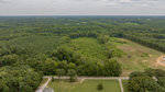 Aerial view of a suburban landscape along Lot 4 Satterwhite Point Road, Henderson NC, showing a road, adjacent homes, and expansive forested areas.