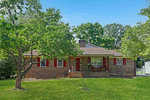A single-story brick house with red shutters at 174 Willow Oak Drive, fronted by a well-kept lawn and a leafy tree on a sunny day.