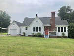 A white single-story house with a gabled roof featuring a red front door and an attached garage situated on a grassy lawn at 306 Bearpond Road, Henderson NC.