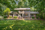 Two-story brick house at 380 Forest Drive, Henderson NC, with white trim surrounded by lush green trees and a well-manicured front lawn.