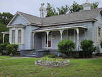 This is a photograph of a single-story, vintage blue house with white trimmings at 280 Chavasse Avenue, Henderson NC, featuring a covered front porch with ornamental supports, a brick