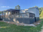 A single-story modular home with an attached front porch and railing. The structure has a sloped roof, is supported by a pier foundation, and is surrounded by a grassy lawn at 519 Waters