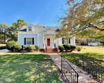 A single-family house at 129 Lakeview Drive, Henderson NC, with white siding and a blue trim, featuring a red front door and a gabled roof, surrounded by a manicured lawn with