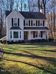 Two-story suburban home at 252 E Stratford Drive, Henderson NC, with a gabled roof and a mix of siding and brick exterior, featuring a prominent chimney, white trim windows, and a