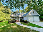A single-family house at 119 Canterbury Court, Henderson NC, with a gabled roof, white siding, and an attached garage, nestled among greenery on a sunny day.
