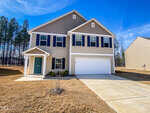 A newly constructed two-story house at 565 E Waycliff Road, Henderson NC, with a two-car garage and beige siding, featuring a turquoise front door under a clear blue sky.
