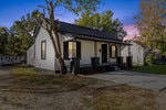 A small, white house with a black shingled roof and dark-trimmed windows sits under a twilight sky at 808 S Carolina Avenue, Henderson NC, surrounded by bare trees and a freshly