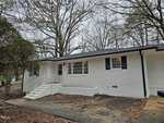 A white single-story brick house at 118 Wester Avenue, Henderson NC, with black trim, featuring multiple windows, a white front door, and a set of white stairs leading to the entrance.