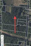 Aerial map view showing a red arrow pointing north over a forested area near Oxford. Several property boundary lines are visible alongside 7029 N NC 15 Highway, with a road on the right. Navigation symbols appear at the bottom left corner of the map.