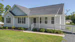 Nestled in Franklinton, the single-story house at 2514 Wes Sandling Road boasts gray siding, dark shutters, and a black shingled roof. A covered front porch with white railing and ramp overlooks a well-kept lawn and small shrubs. A satellite dish discreetly adorns the roof.