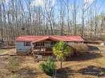 Nestled at 3514 Topaz Street, a cozy house with a red roof and covered porch stands amid bare trees in a wooded area. A palm tree and some shrubbery grace the foreground, while the sky above Wake Forest is partly cloudy.