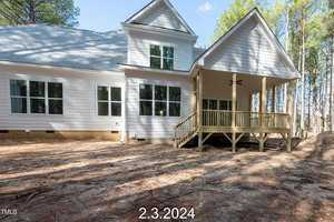 A modern, two-story white house with a spacious porch and large windows, set against a backdrop of tall trees. The date "2.3.2024" is in the foreground.