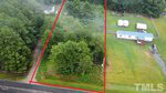 Aerial view of the property at 8612 Robert Morgan Road, outlined in red, featuring a mix of trees and open grassy area. A road runs along the bottom of the image, and two mobile homes are visible on the right near the edge of a wooded area in Bullock.