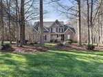 Nestled at 1173 Smith Creek Way in Wake Forest, this two-story house boasts a gray exterior, surrounded by tall trees and a well-maintained lawn. With its large front porch and multiple gables, the home exudes warmth and spaciousness amidst its serene, wooded setting.