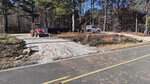 A construction site next to 2089 Suitts Store Road features a parked truck and tractor on a gravel path, surrounded by trees. The area appears to be in a forest setting near Franklinton, under clear blue skies.