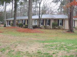 Nestled among tall trees, the single-story brick house with white trim sits gracefully on Butner's 607 19th Street. The front yard, a blend of grass, pine needles, and shrubs, hosts two deer standing close to the home on this overcast day.
