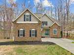 Located at 3564 Saddle Ridge Road, this two-story house boasts a stone and siding exterior with a charming covered porch and garage. Surrounded by leafless trees under a partly cloudy sky, the home's welcoming driveway seamlessly guides you to its entrance.