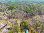 Aerial view of a wooded area with a triangular plot outlined in yellow near 7044 Old West Lane, Oxford. The surrounding landscape features dense forests, a few houses, and open spaces under a clear sky.