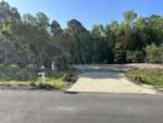 A cleared empty lot at 431 Mayview Drive features a concrete driveway surrounded by lush trees and greenery under a clear blue sky. A mailbox stands on the left side near the road, marking this serene Creedmoor location.