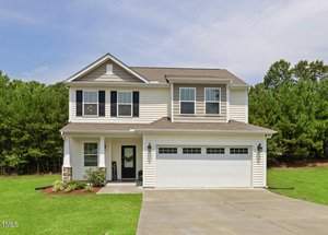 Nestled at 100 Torrance Court, this charming two-story beige house features a garage and a neatly trimmed lawn. With black shutters and a welcoming front porch, it's framed by trees and a clear sky, creating an inviting stem of suburban tranquility.