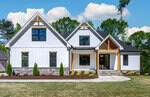 Located at 995 Browning Place in Youngsville, this modern suburban house features a white exterior with stone accents and black-framed windows. It boasts a gabled roof, a covered entryway with wooden beams, and is complemented by a well-maintained front lawn against a backdrop of trees.